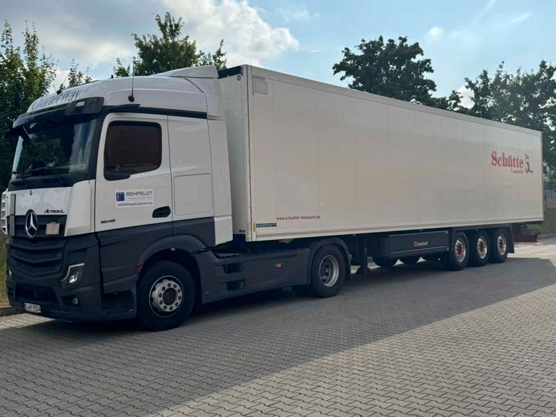 Weißer Sattelschlepper mit langem Anhänger auf Asphalt geparkt, Aufschrift „Schulz“.