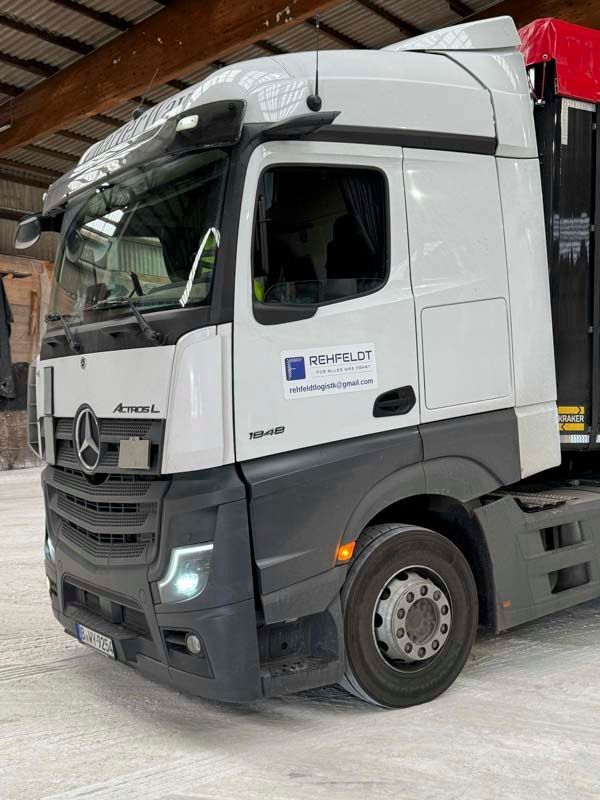 Weißer Mercedes-Benz Actros-Sattelzug mit Firmenlogo, in einem Gebäude geparkt.