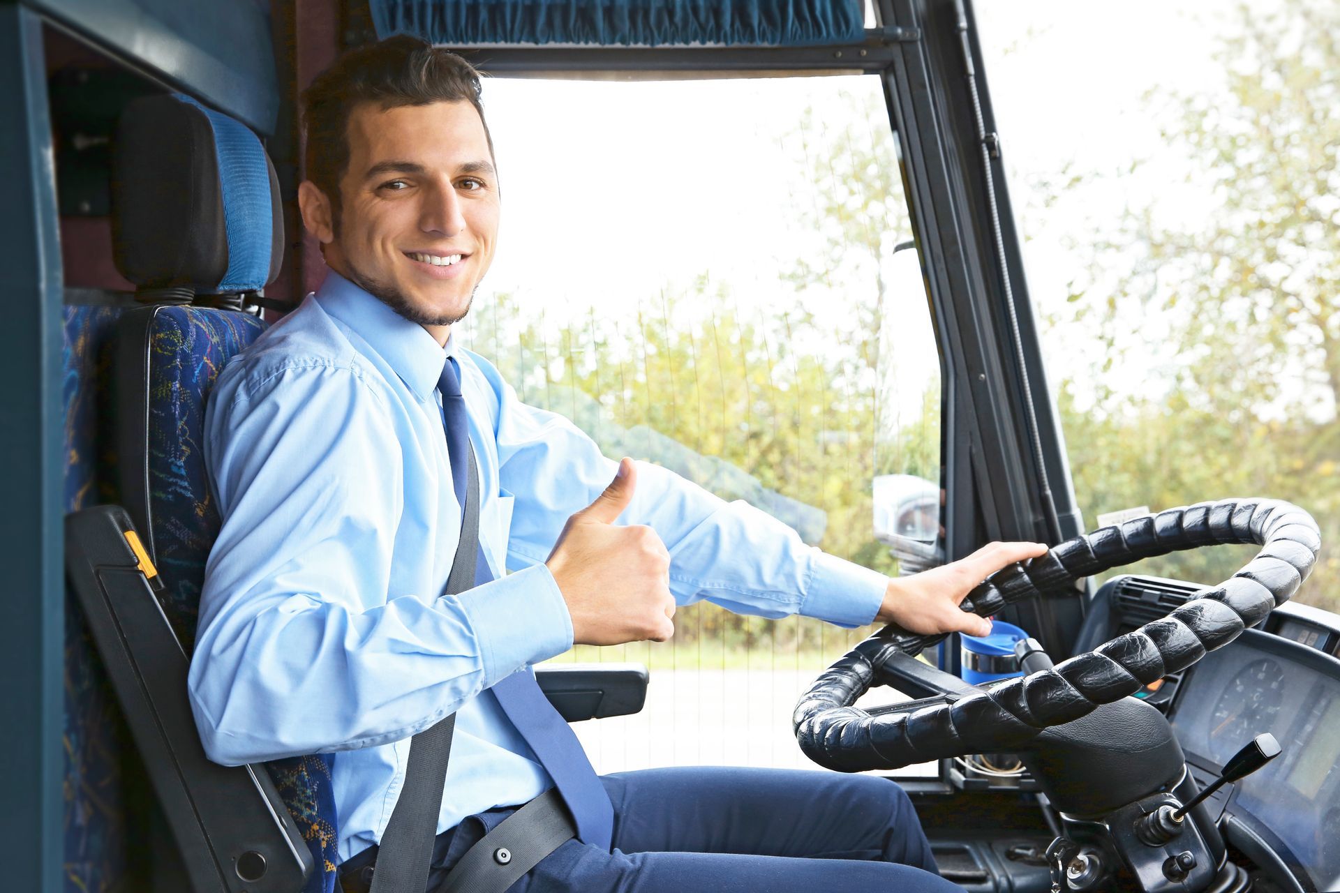 Der Lkw-Fahrschüler lächelt in der Fahrerkabine und zeigt mit dem Daumen nach oben auf das Lenkrad.