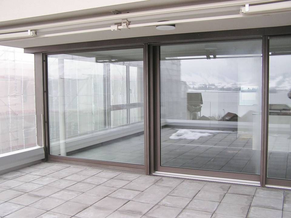Ein Balkon mit Glasschiebetüren und Blick auf ein Gewässer. Foto von der Adolf Nussbaumer Fensterbau AG