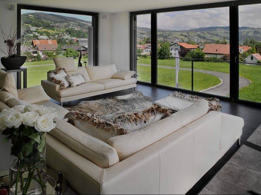 Ein Wohnzimmer mit vielen Fenstern und einer Couch. Foto von der Adolf Nussbaumer Fensterbau AG