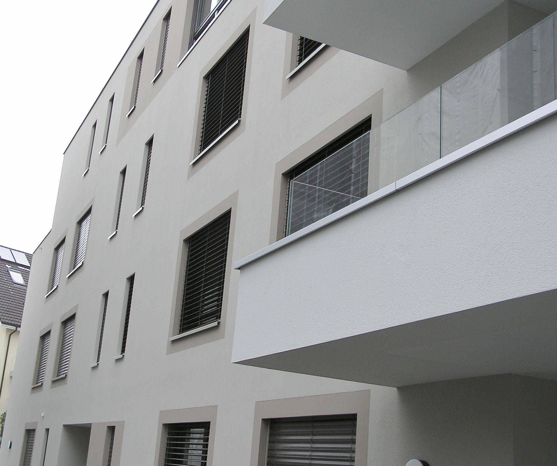 Ein weißes Gebäude mit einem Balkon und vielen Fenstern