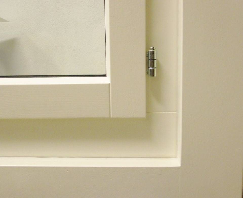 Eine Nahaufnahme eines weissen Fensters mit einem Metallscharnier. Foto von der Adolf Nussbaumer Fensterbau AG