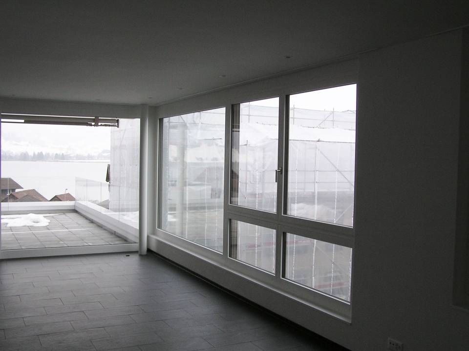 Ein leerer Raum mit vielen Fenstern und Blick auf ein Gewässer. Foto von der Adolf Nussbaumer Fensterbau AG