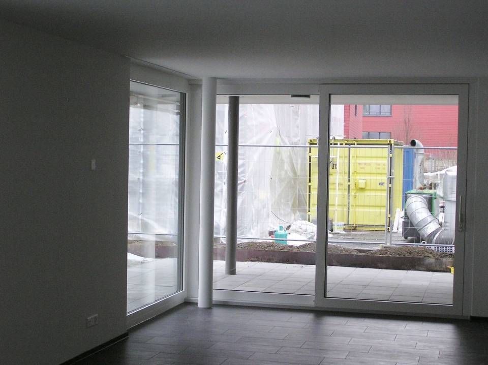 Ein Raum mit vielen Fenstern und einem gelben Container im Hintergrund