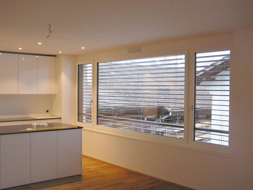 Eine Nahaufnahme eines weissen Fensters mit einem Metallscharnier. Foto von der Adolf Nussbaumer Fensterbau AG