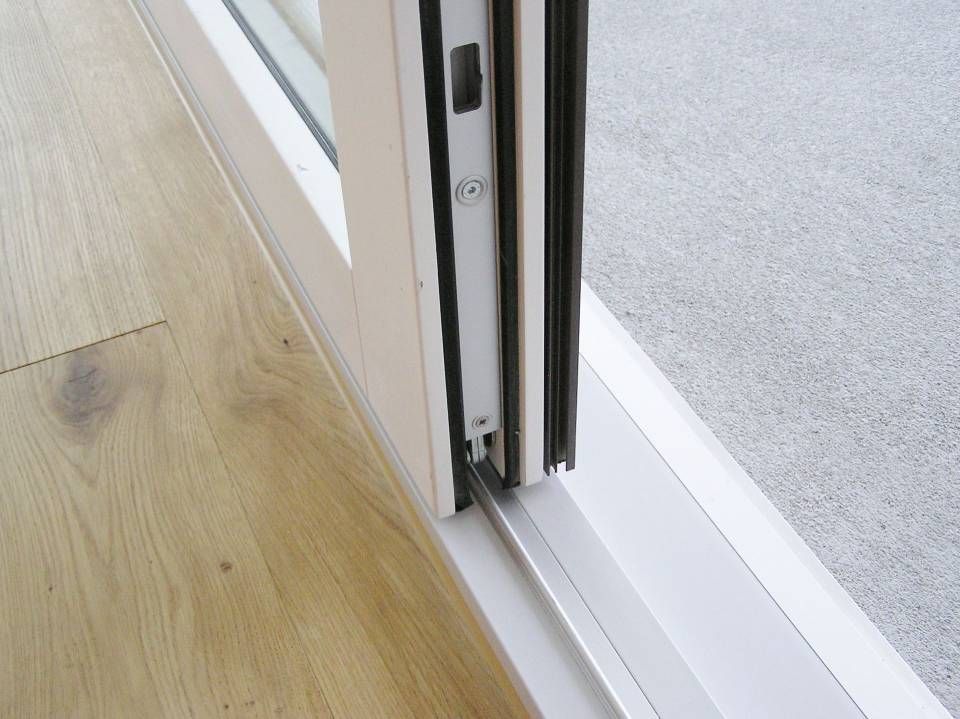 Eine Nahaufnahme einer Glasschiebetür auf einem Holzboden. Foto von der Adolf Nussbaumer Fensterbau AG