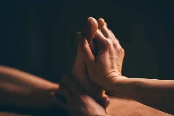 Una mujer le está dando un masaje de pies a un hombre.