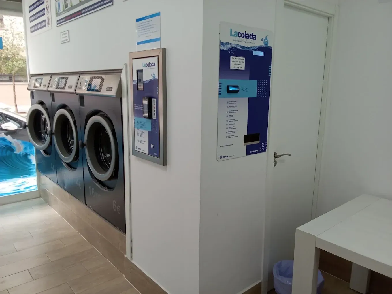 Lavandería con lavadoras, fregadero y dispensador de desinfectante fijado a la pared junto a la zona de la piscina