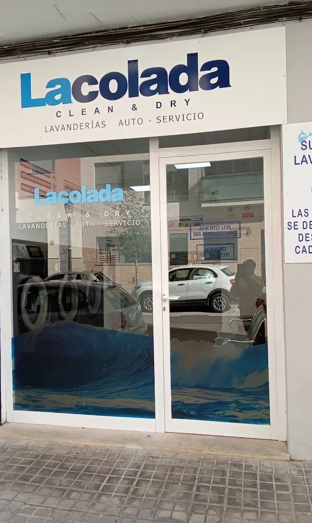 Fachada de la lavandería La Colada, con un letrero azul y blanco y puertas de vidrio en una acera urbana