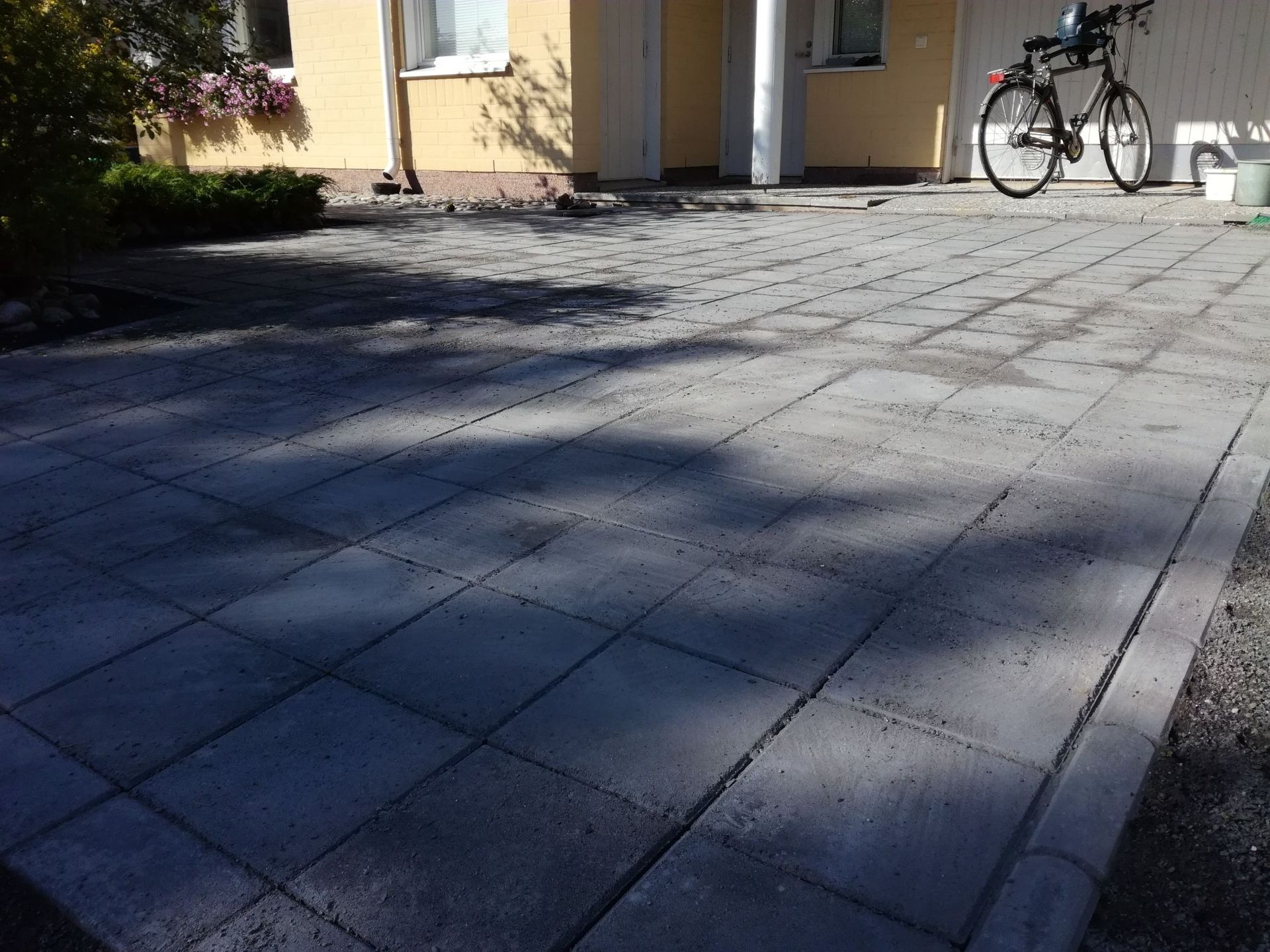 Rakennuksen ulkopuolella oleva päällystetty sisäpiha, jossa polkupyörä pysäköitynä seinän lähelle.