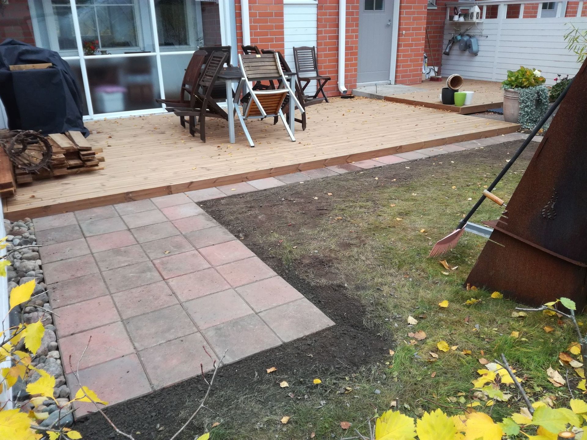 Takapihan patio, jossa on laattoja, ulkotuoleja, grilli ja nurmialue talon vieressä