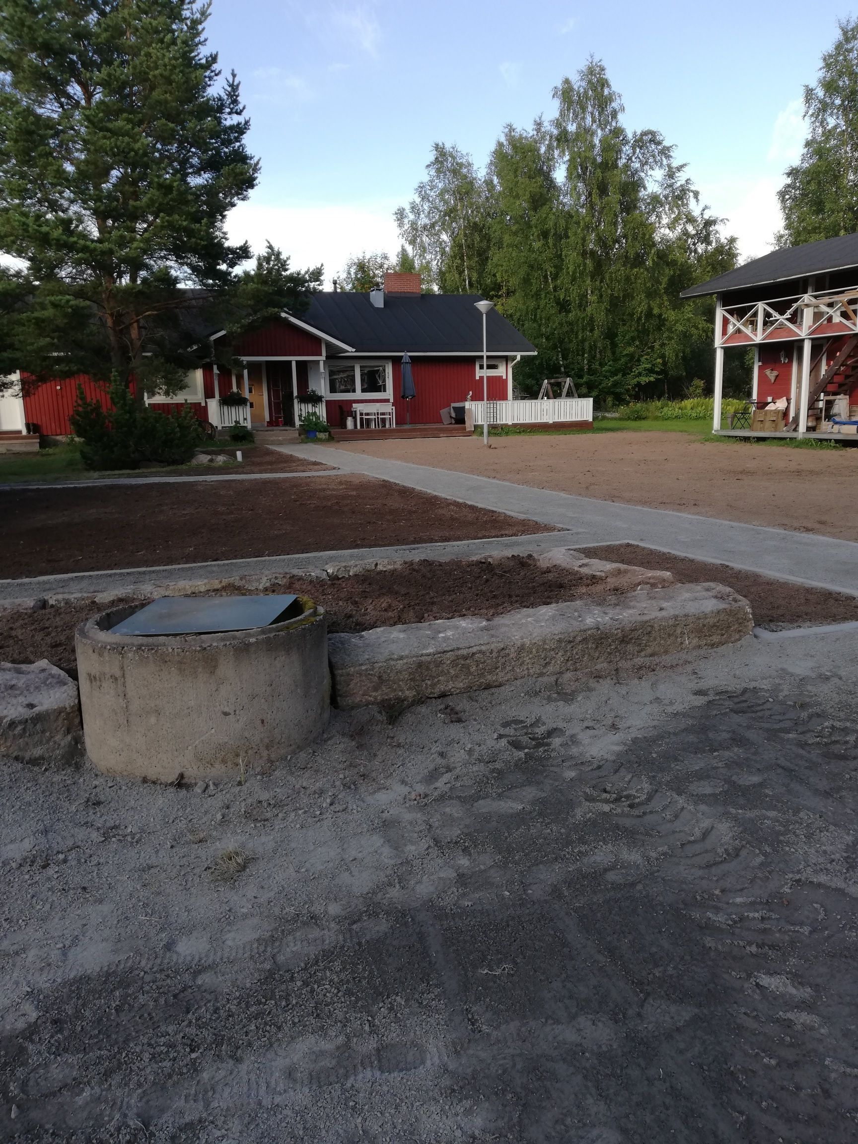Sorapiha, jossa nuotiopaikka, punaiset rakennukset ja puut kirkkaan taivaan alla