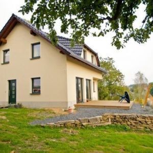 Gelbes Einfamilienhaus mit Satteldach im Grünen.