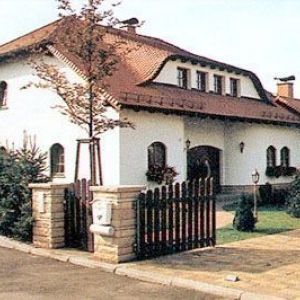 Obergeschoss mit Balkon, Metallgeländer und blauen Dachziegeln.