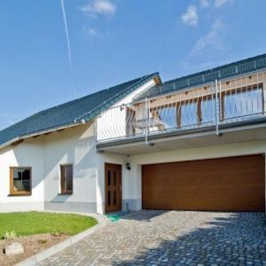 Dachbalkon mit Metallgeländer unter blauem Himmel.