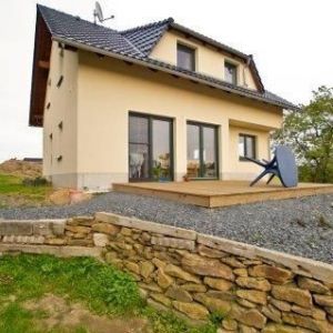 Hausrückseite mit Terrasse und großen Fenstertüren.