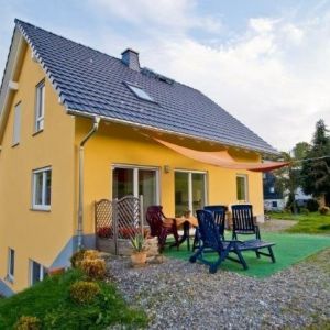 Symmetrische Giebelfassade eines beigen Einfamilienhauses.