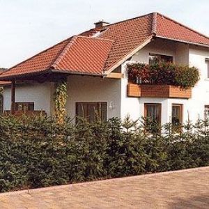 Einfamilienhaus mit Ziegeldach und bepflanztem Holzbalkon.