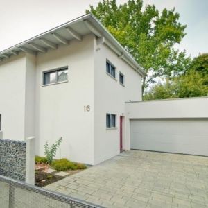 Perspektivische Ansicht einer hellen Fassade unter einem breiten Dachüberstand.