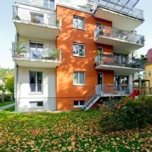 Moderne Wohnanlage mit orangefarbener Fassade und Glasbalkonen.