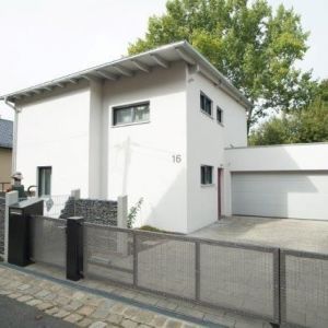 Schlichte, moderne Hauswand in Weiß mit kleinen Fenstern und Flachdach-Element.