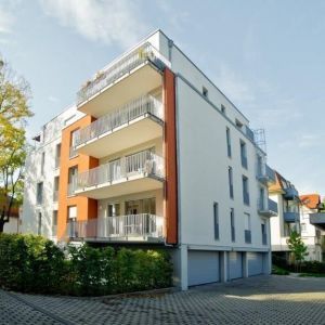 Weiß-oranges Mehrfamilienhaus mit versetzten Balkonen.