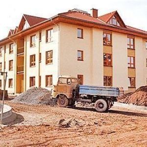 Großes Wohngebäude in Ocker mit Satteldach.