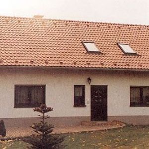 Schlichte Fassade eines Wohnhauses mit zwei Dachfenstern in einer gleichmäßigen roten Ziegelstruktur.