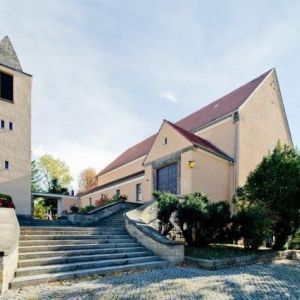 Seitenansicht einer sanierten Kirche mit hellem Putz, hohem Glockenturm und rotem Ziegeldach.