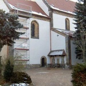 Sanierung einer weißen Kirchenfassade mit sichtbarem Baugerüst an einem Rundbogenfenster.