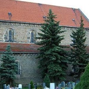 Blick auf ein Kirchengebäude mit rotem Steildach und Ansätzen eines Baugerüsts an der Fassade.