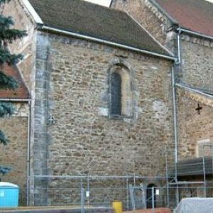 Ansicht einer romanischen oder gotischen Kirche mit weißer Fassade und markant abgestuften Dachflächen.