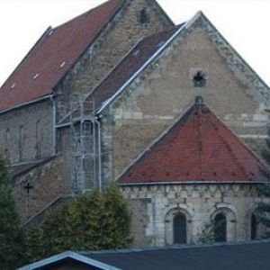 Detailaufnahme einer historischen Kirchenwand aus unbehauenem Naturstein mit einem Rundbogenfenster.