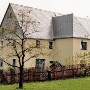 Klassisches Steingebäude mit hellem Putz und grauem Schieferdach.