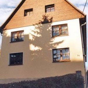 Kombinierte Fassade aus weißem Putz und hellem Holzgiebel.