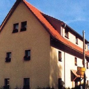 Graue Fassade mit Sprossenfenstern und blauen Klappläden.