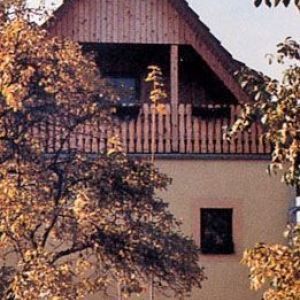 Giebelseite eines Holzhauses mit tiefem Balkon unter dem Dach.