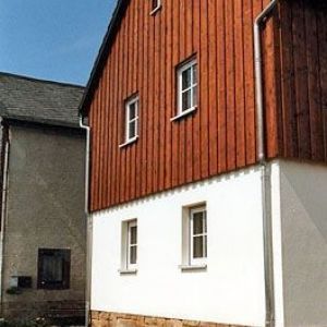 Vertikale Holzfassade eines Bauernhauses mit Sprossenfenstern.