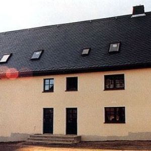 Eckansicht eines weißen Gebäudes mit Erker und Turmelement.