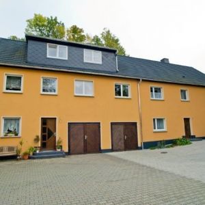 Saniertes Mehrfamilienhaus in Ocker mit anthrazitfarbenem Dachgeschoss.