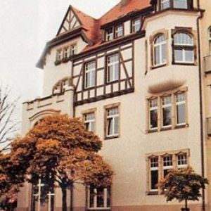 Prächtiges Eckgebäude mit weißem Putz, hölzernen Erkern und markanten Fachwerk-Elementen im oberen Bereich.