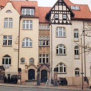 Detailreiche Fassade eines sanierten Altbaus mit Rundbogenfenstern im Erdgeschoss und einem markanten Fachwerkgiebel.