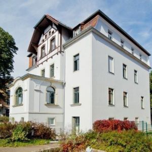Eckansicht eines modern sanierten Altbaus mit glattem weißen Putz und einem Giebel in dunkler Fachwerkoptik.