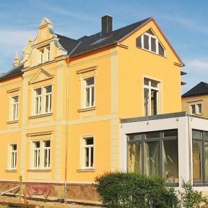 Gelbes Stadthaus mit verzierten Fensterrahmen und prachtvollem Giebel.