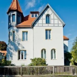 Modern sanierte Fassade in kräftigem Orange mit neuen weißen Fenstern und überdachtem Eingangsbereich.