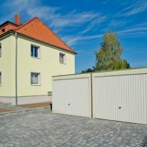 Detailansicht einer weiß verputzten Villa mit dekorativen Fachwerkelementen am Giebel und einem Eckturm.