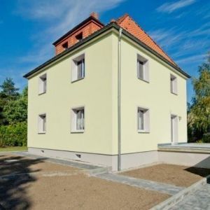 Außenansicht eines gepflegten, hellen Stadthauses mit markantem Erker und klassischer Architektur.