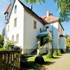 Prachtvoll sanierte Villa in Gelb mit traditionellen grünen Fensterläden und Rundbogenfenstern im Erdgeschoss.