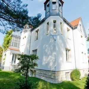 Gelbe Hausfassade mit mehreren Fenstern und Satellitenschüsseln.